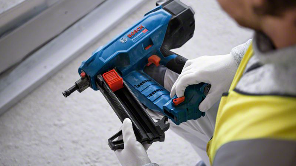 En blå Bosch Professional batteridriven spikpistol hålls av en person.