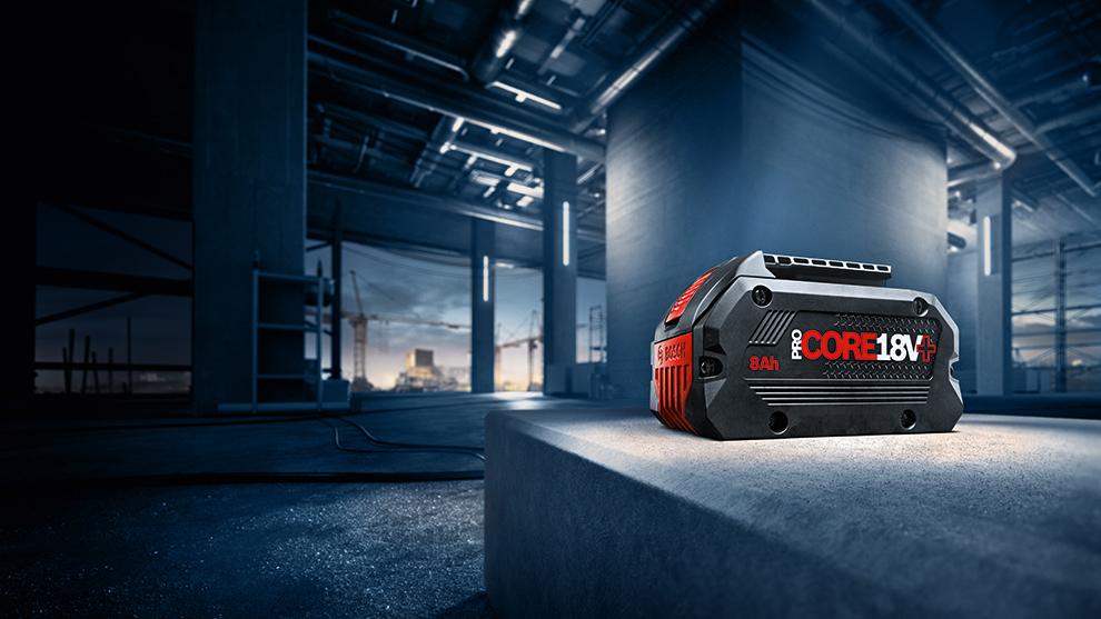 Μαύρη μπαταρία Bosch Professional με κόκκινη επιγραφή σε ένα σκυρόδεμα.