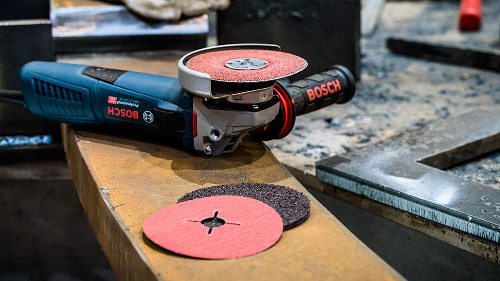 En Bosch Professional vinkelsliber ligger på et arbejdsbord med skiver.