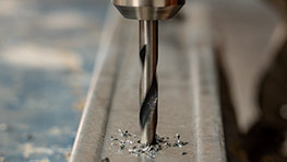 En Bosch Professional borr snurrar över en metallbit med spån.