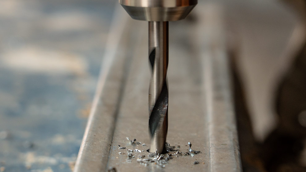 Un trapano professionale Bosch ruota sopra un pezzo di metallo con trucioli.