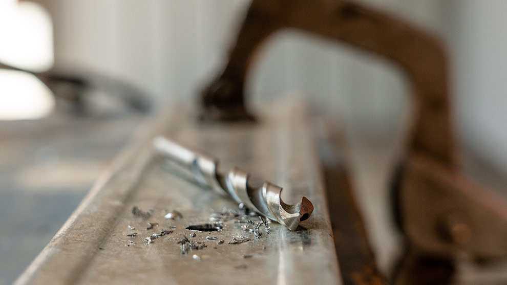 Un trapano è posato su una superficie metallica, circondato da trucioli.