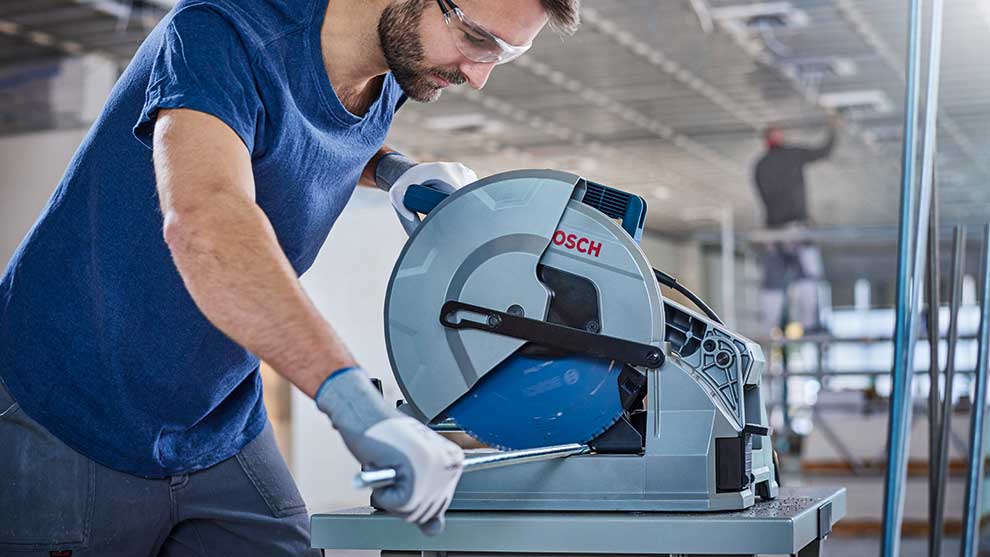 Een man in blauwe kleding bedient een Bosch Professional cirkelzaag.