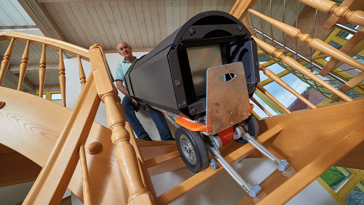 Muž nese černou krabici s nářadím dolů po schodech.