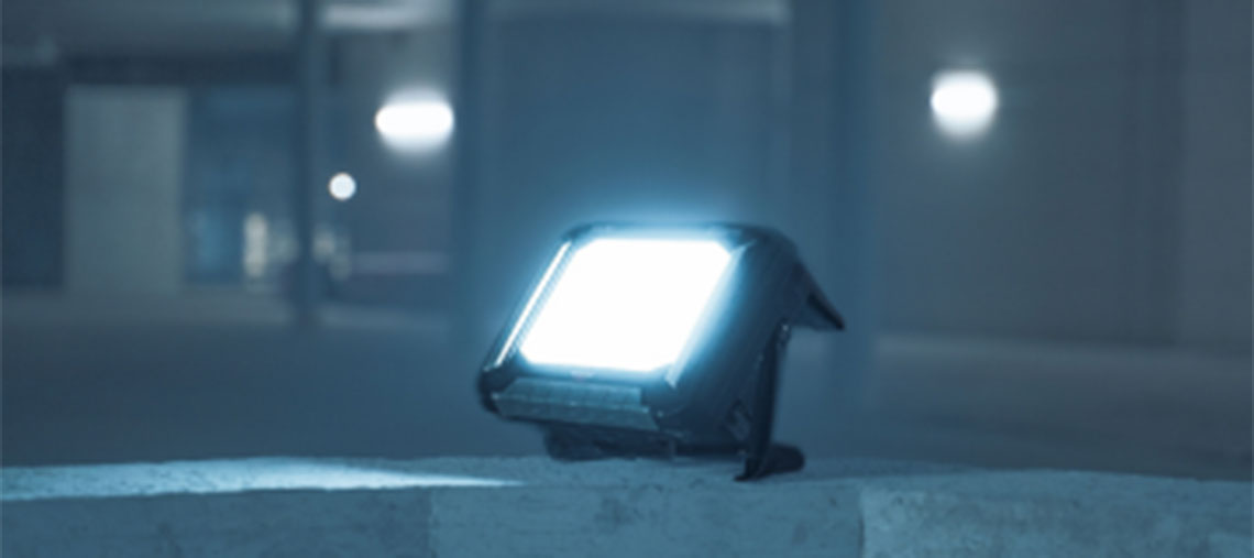 Stavební reflektor Bosch Professional osvětluje šedý povrch.