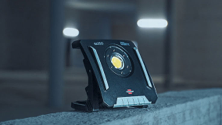 Černý stavební reflektor Bosch Professional stojí na betonovém podstavci.