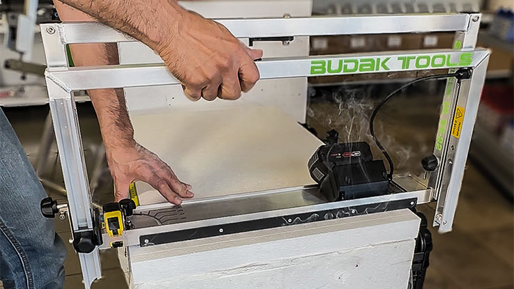 Osoba používá zařízení Budak Tools k řezání materiálu.