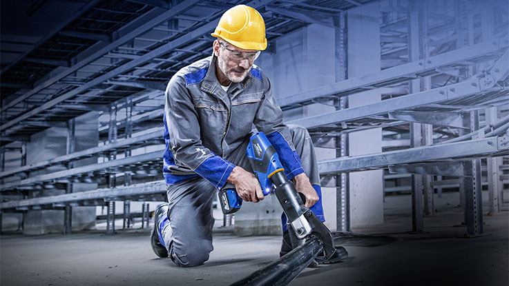 Muž v pracovním oblečení používá modré nářadí Bosch.