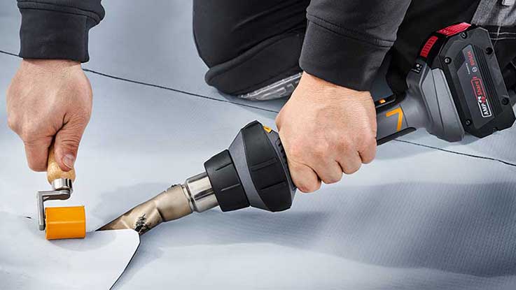 Osoba zpracovává fólii pomocí horkovzdušné pistole Bosch.