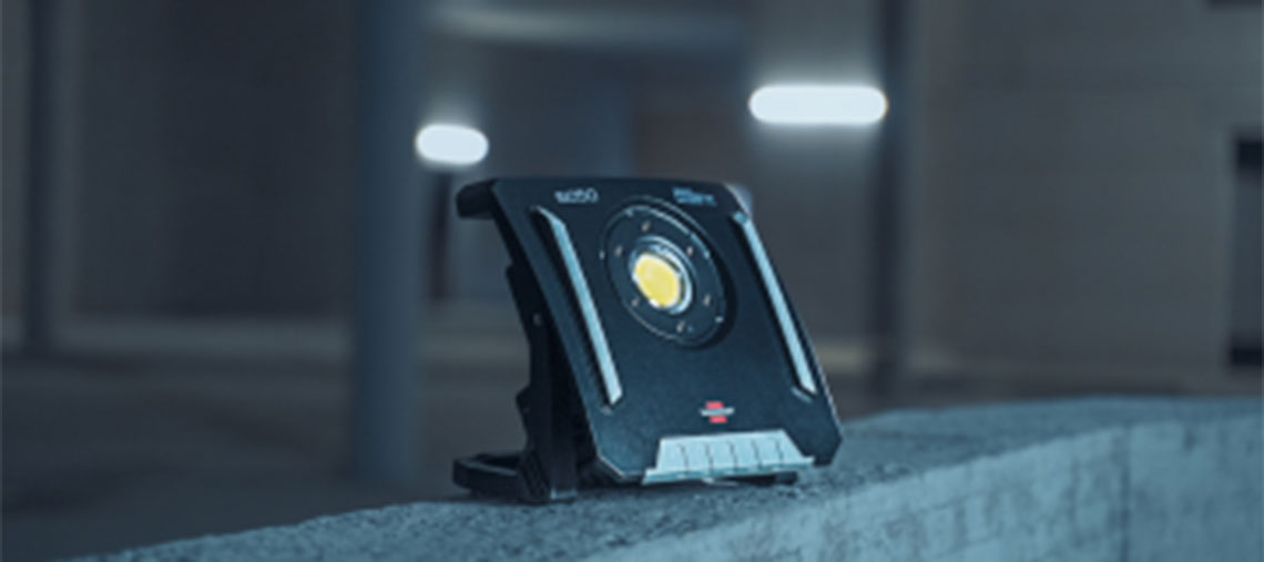 Черна строителна лампа Bosch Professional стои на бетонна повърхност.