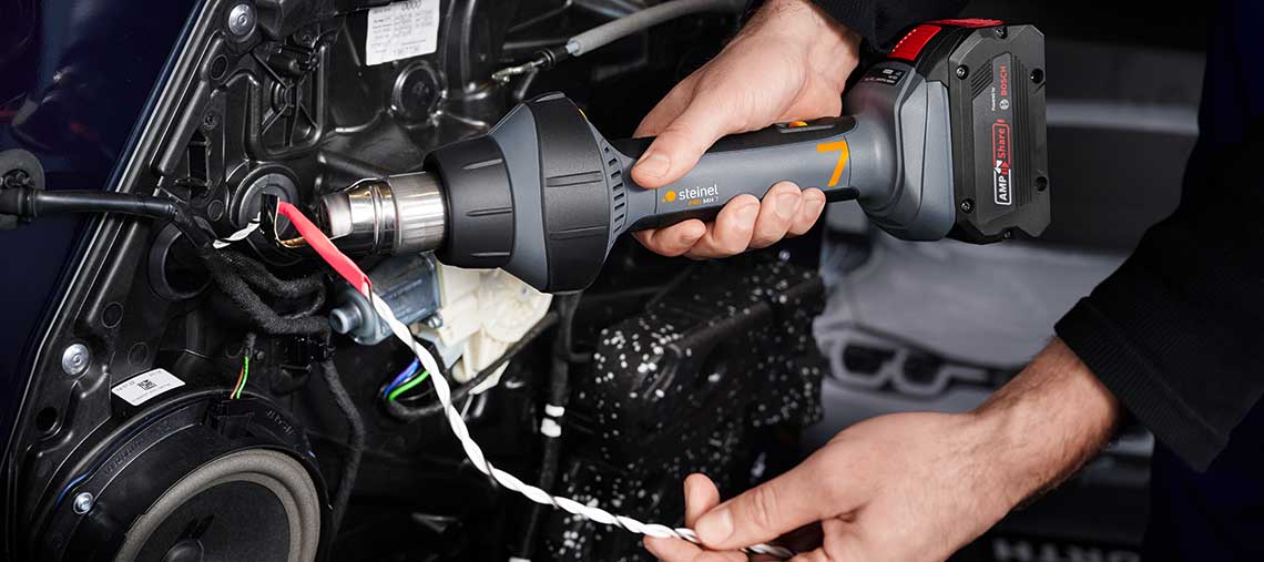 Занаятчия използва сешоар Steinel за горещ въздух на кабел.