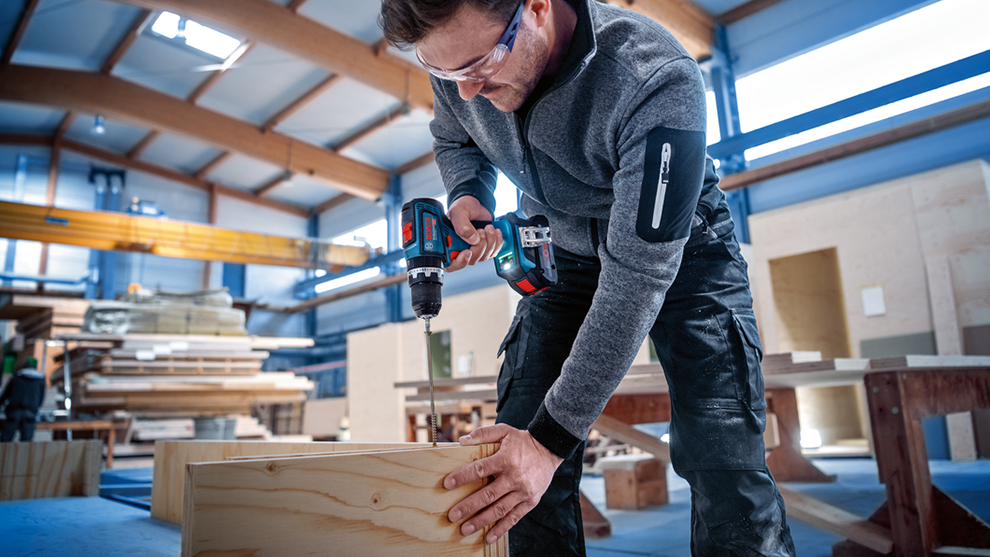 A craftsman uses a Bosch Professional cordless drill on a piece of wood.