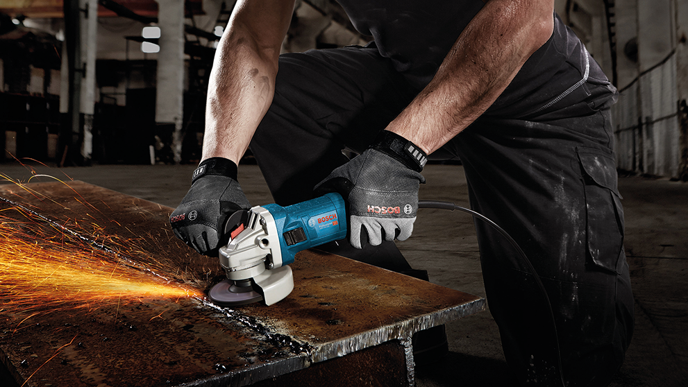A craftsman uses a blue Bosch angle grinder on metal.