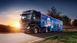 Črn Mercedesov tovornjak z modrim reklamnim motivom Bosch vozi po cesti.