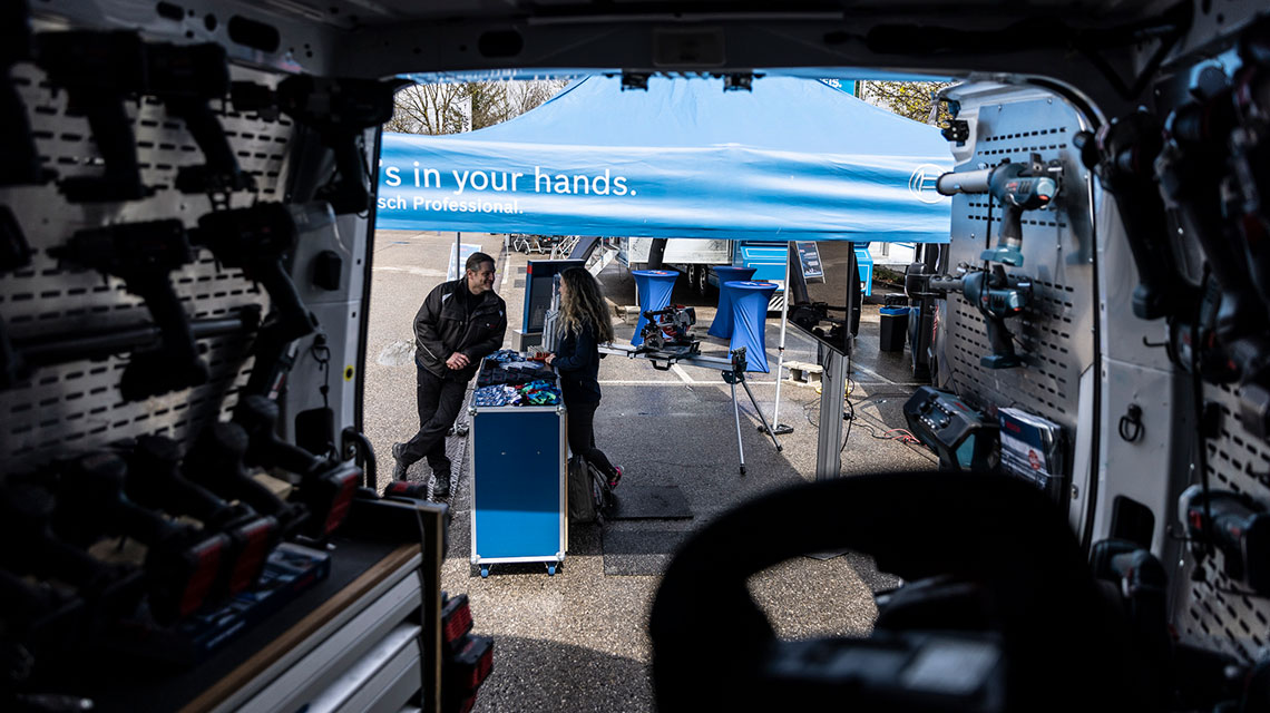 En Bosch Professional stand med to personer under et blåt telt.