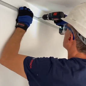 Un artesano con un taladro atornillador Bosch está instalando una tira en la pared.