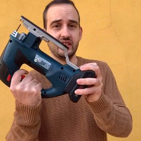 Un hombre sostiene una sierra de calar Bosch Professional frente a una pared amarilla.