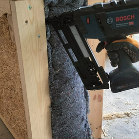 Un clavador a batería Bosch Professional fija material aislante a una pared.