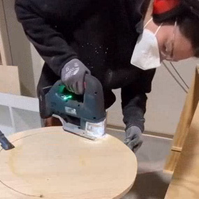 Un hombre está cortando madera con una sierra eléctrica en una mesa.