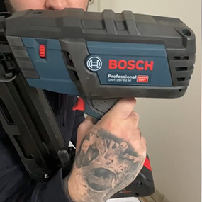 Un cloueur à batterie Bosch Professional est tenu par une personne.