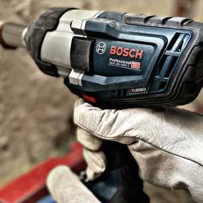 Una mano tiene un avvitatore a batteria Bosch Professional con superficie grigia.