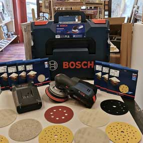 Un levigatore a batteria Bosch Professional è davanti a una cassetta degli attrezzi.
