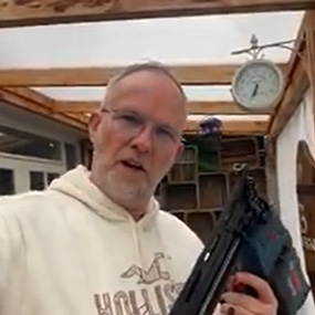 Een man met een bril houdt een blauwe Bosch Professional accunagelaar vast.