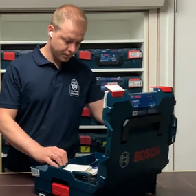 Een man in een blauw shirt opent een Bosch gereedschapskist.