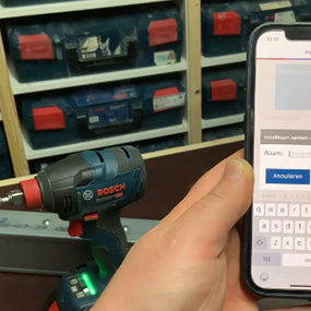 Een Bosch Professional accuschroefmachine staat op een tafel, naast een mobiele telefoon.