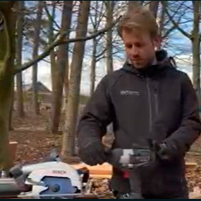 Een man in werkkleding houdt een Bosch Professional gereedschap vast in het bos.