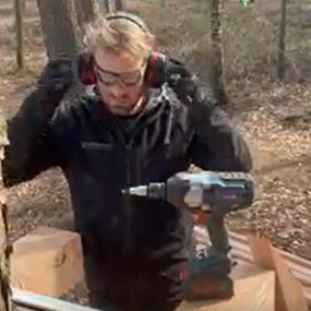 Een man met gehoorbescherming gebruikt een Bosch Professional accuboormachine in het bos.
