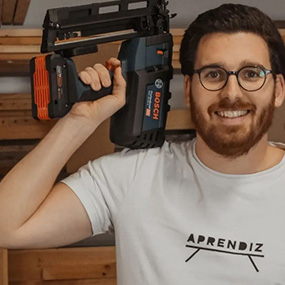 Homem de óculos segura um grampeador sem fio azul Bosch Professional na mão.