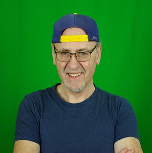 Un homme souriant avec des lunettes porte une casquette bleue sur la tête.