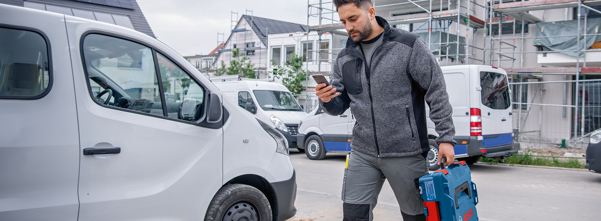 Ein Mann mit Werkzeugtasche geht an einem Lieferwagen vorbei.