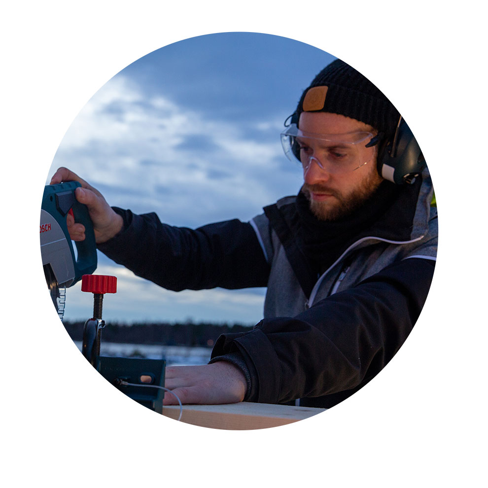 Mees kaitseprillidega kasutab Bosch'i pendelsaagi õues.