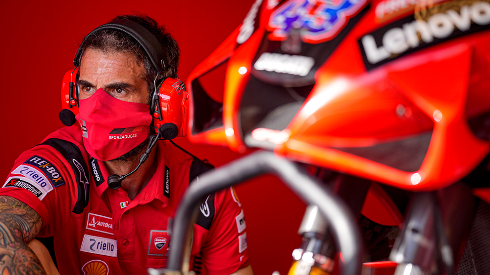 Punases riietuses mehhaanik istub punase mootorratta kõrval.