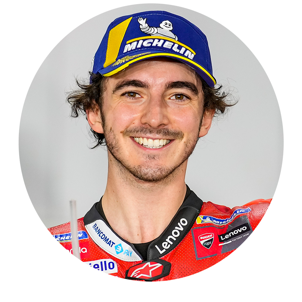 Naeratus näoga mees mootorrattajakis ja sinises mütsis poseerib sõbralikult.