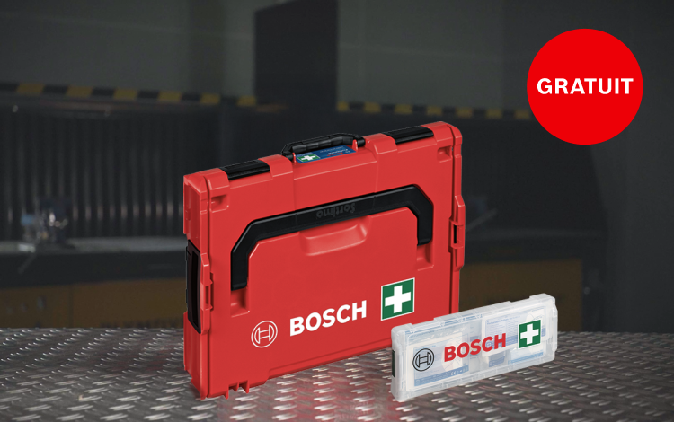 Une boîte à outils Bosch rouge est posée sur une table en métal à côté d'une trousse de premiers secours.