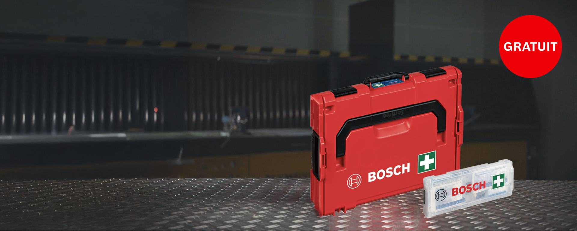 Une boîte à outils Bosch rouge est posée sur une table en métal, à côté d'une boîte.