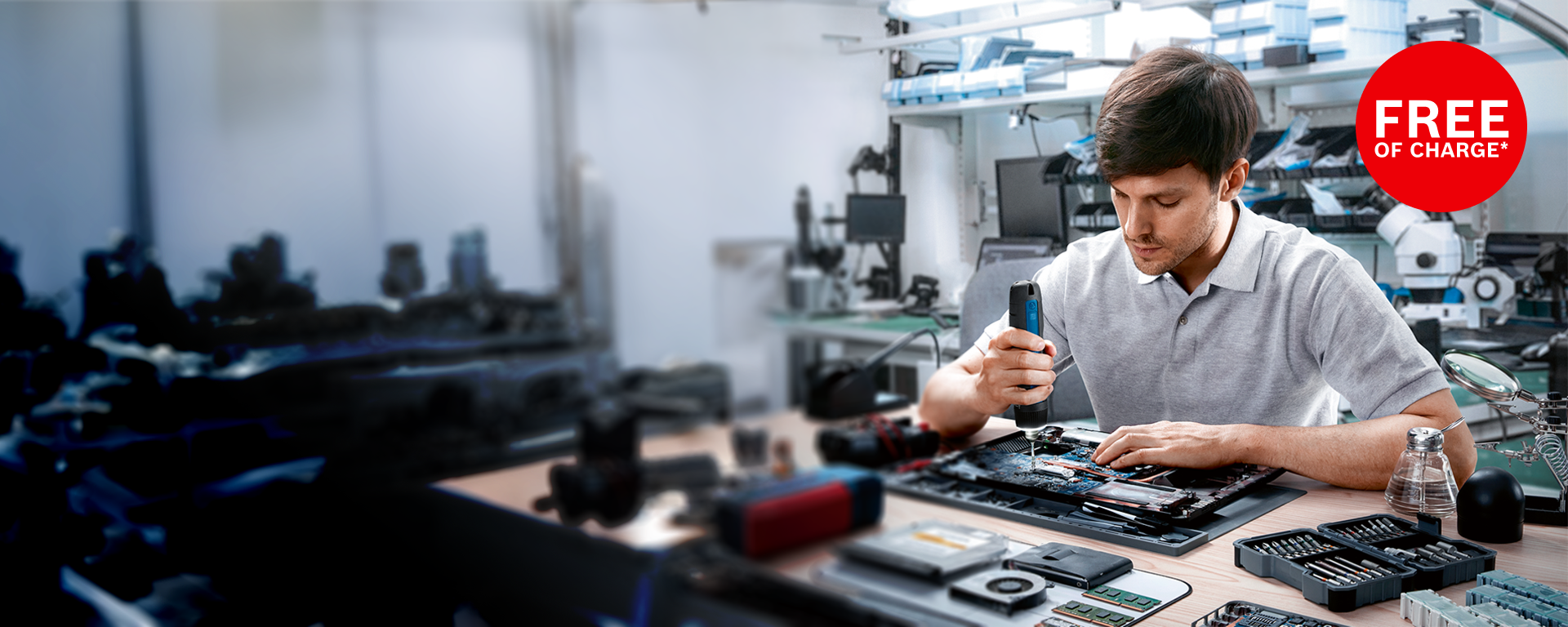 A man is working with a Bosch tool on a laptop in a workshop.