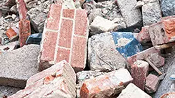 Vários tijolos e pedaços de concreto estão empilhados caoticamente um sobre o outro.