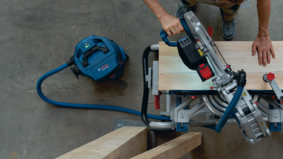 A Bosch Professional circular saw cuts wood on a table.