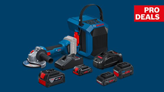 Ein blauer Akku-Winkelschleifer, mehrere Akkus und ein tragbarer Lautsprecher auf dunklem Hintergrund.