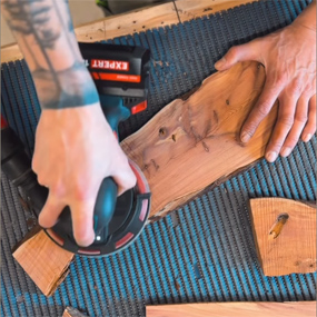 Una mano sostiene un destornillador inalámbrico Bosch Professional negro, que trabaja sobre un trozo de madera. Rodeado de restos de madera.