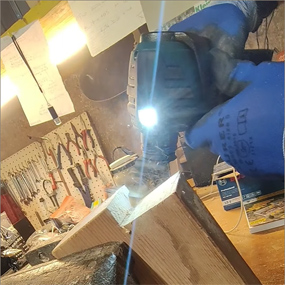 Un avvitatore a batteria Bosch Professional con luce LED viene utilizzato su un pezzo di legno per lavorarlo. Sullo sfondo si vedono strumenti e materiali da officina.
