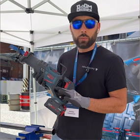 Un uomo con occhiali da sole e guanti tiene uno strumento a batteria Bosch Professional in una tenda.