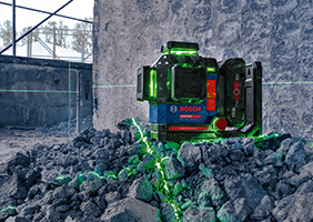 Зелений лазер Bosch Professional на купі сірого каміння в будівельному середовищі.