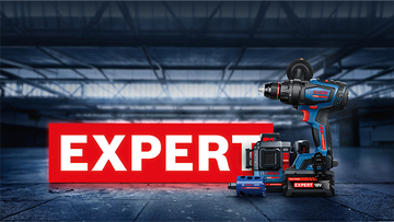 Akumulátorový šroubovák a toolbox před červenou cedulí "EXPERT" v dílně.