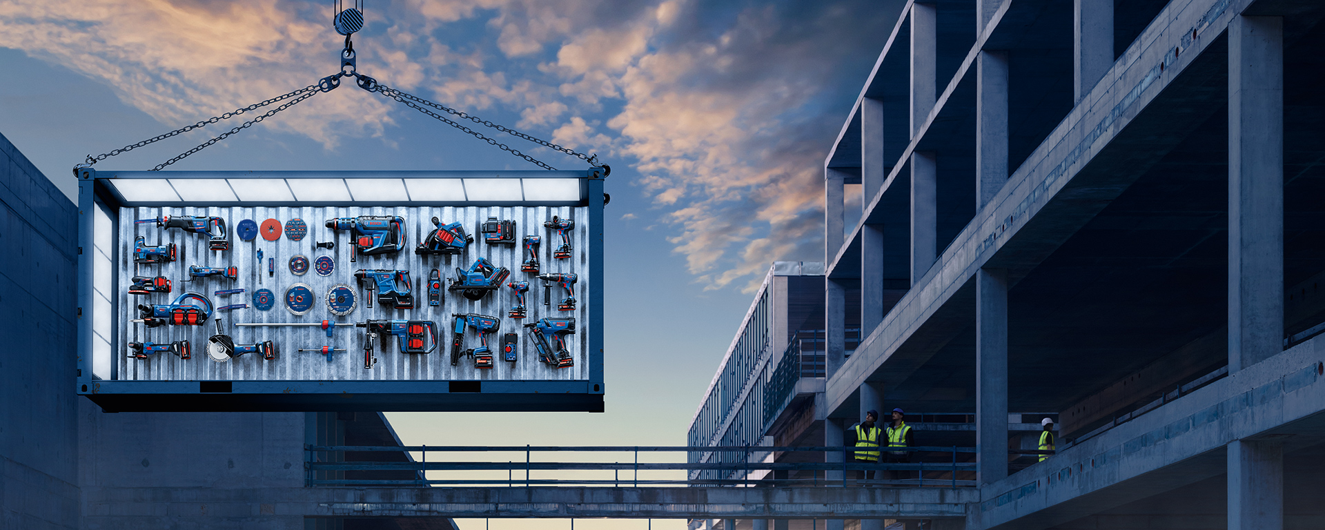 A container with several blue and red tools hovers over a construction site. Workers are observing.