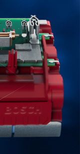 Avatud sinine tööriistakast, kus on neli punast akut ja laadija, hallil põrandal.